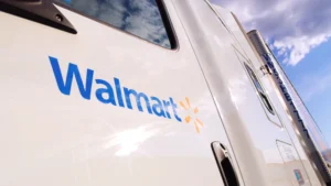 Side view of a Walmart truck on a road with a cloudy sky in the background.