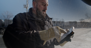 Truck driver interacting with an ISAAC Instruments tablet in snowy conditions, showing the device's durability and reliability.