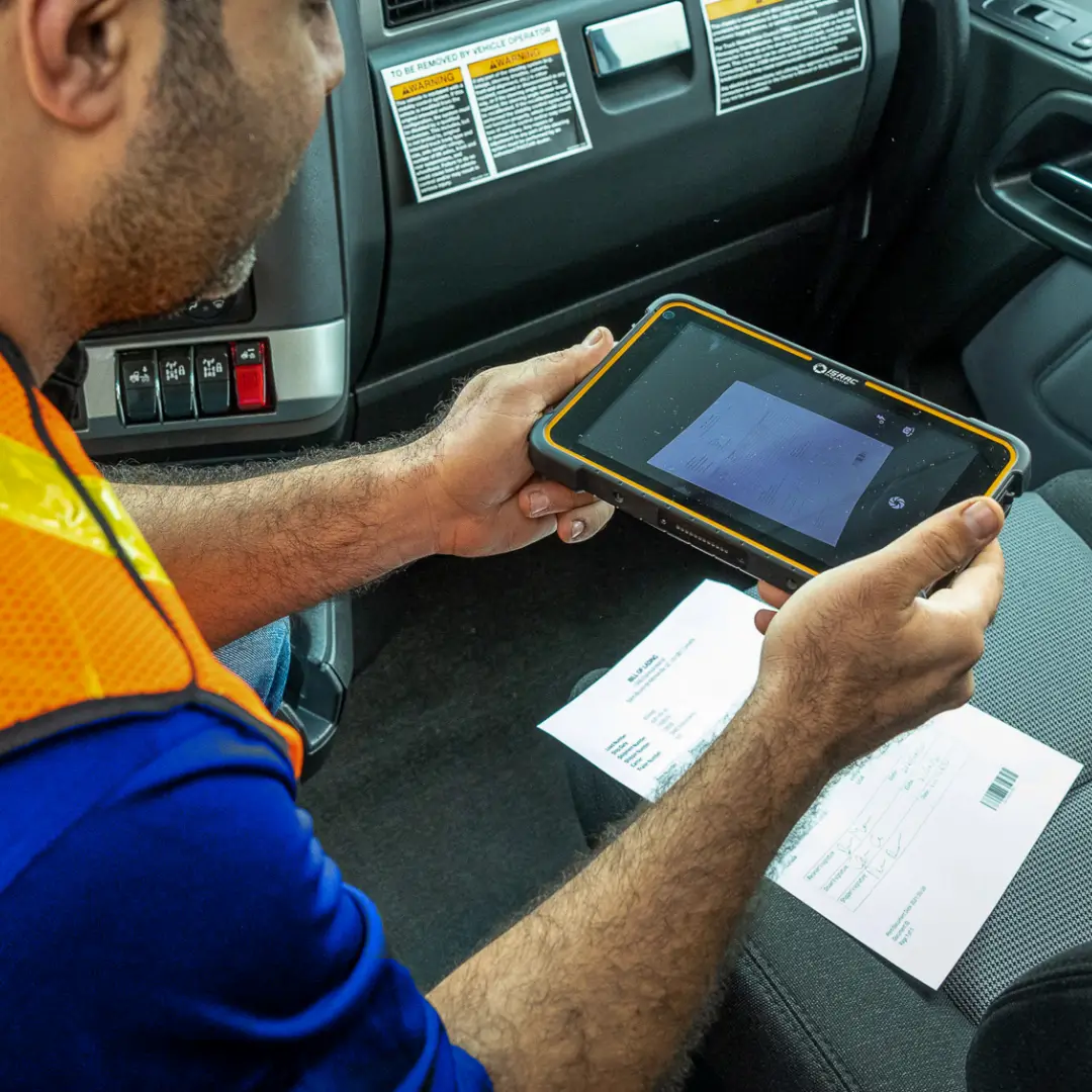 Truck driver scanning documents on a tablet inside the truck.