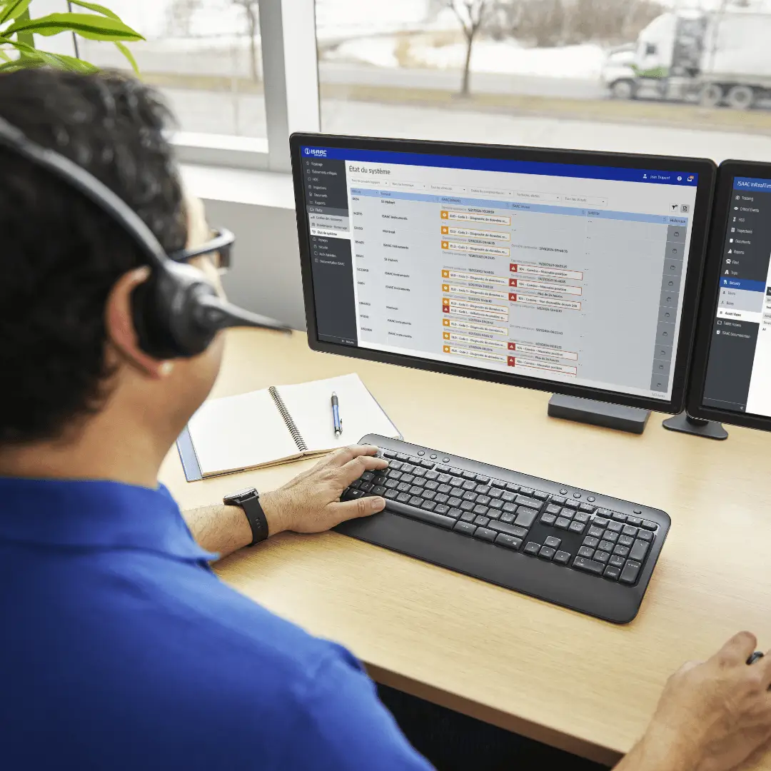 Personnel de bureau utilisant le logiciel de gestion de flotte ISAAC sur un ordinateur.