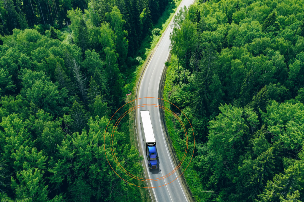 Vue aérienne d’un camion roulant sur une route forestière avec une superposition de suivi GPS.