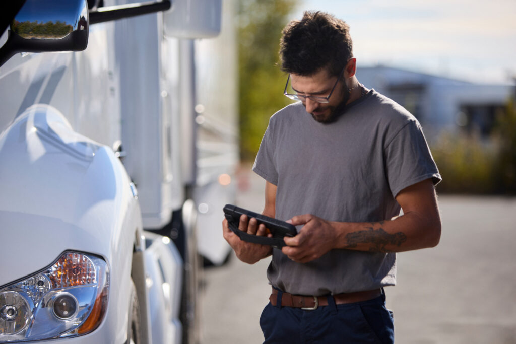 Conducteur de camion effectuant une inspection du véhicule à l’aide d’une tablette numérique.