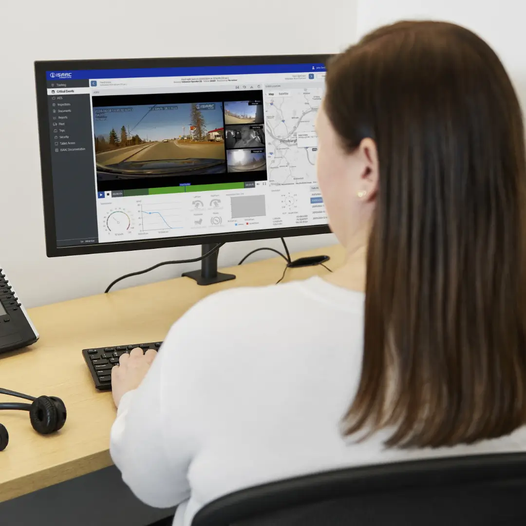 A dispatcher monitoring ISAAC’s trucking operations software on a desktop computer screen showing real-time data and video feeds.