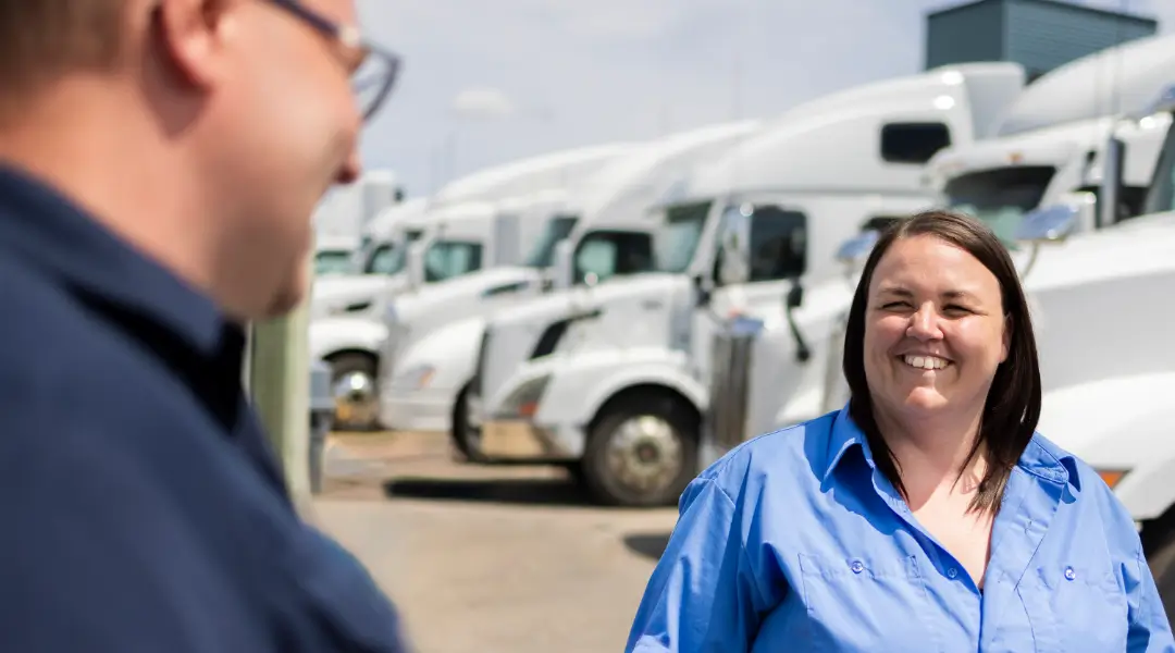 Two team members discussing in front of a row of white trucks, showcasing the logistics industry focus of ISAAC Instruments.