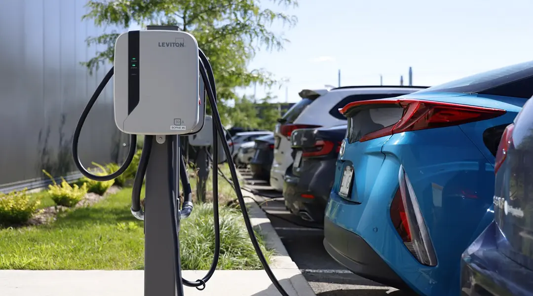 Electric vehicle charging station in the ISAAC Instruments parking lot with EVs plugged in, promoting sustainability initiatives.