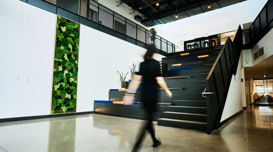 Modern open-concept office space at ISAAC Instruments featuring a green wall and collaborative staircase area.